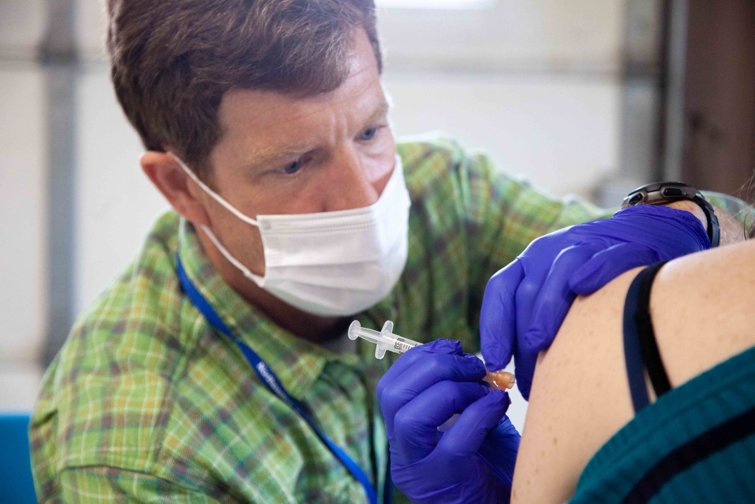 Masked man giving injection in arm