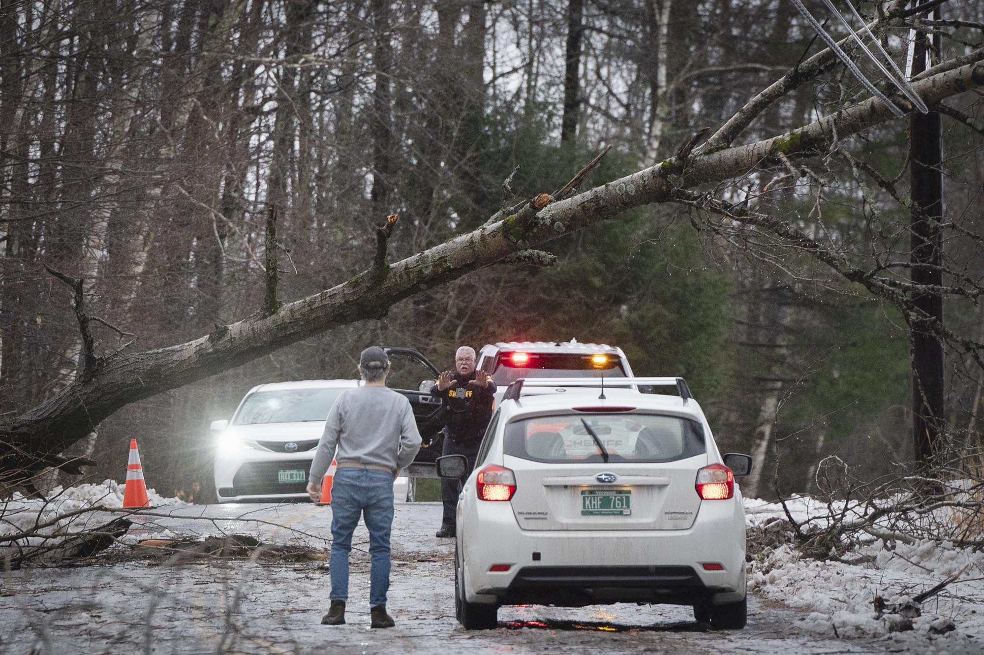 A tree falls on a car in a snowy area.
