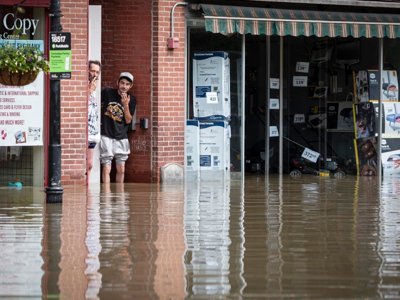 a man is standing in a flooded street near a store.