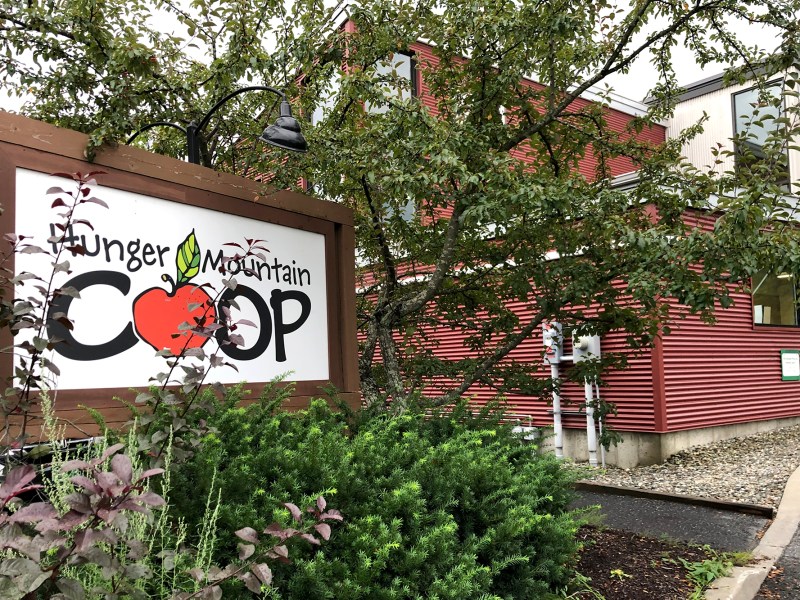 A red Hunger Mountain Co-op building with a sign next to it.