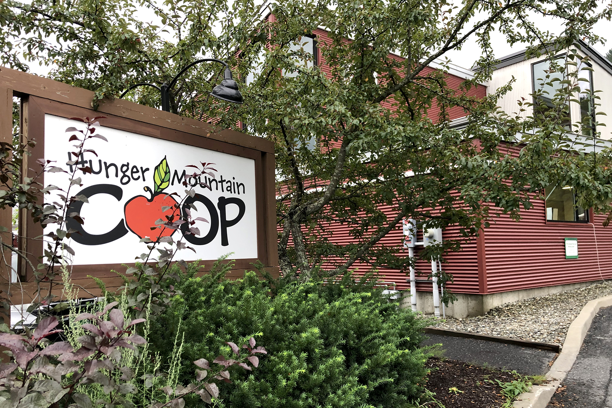 A red Hunger Mountain Co-op building with a sign next to it.