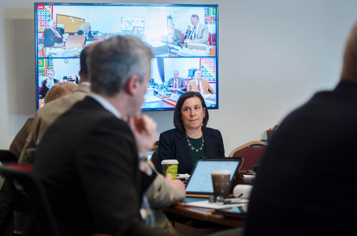 People sitting around a conference table with a screen displaying a video call in a meeting room.