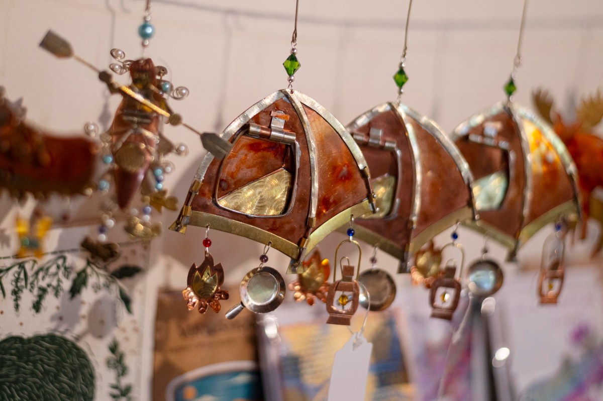A row of decorative hanging ornaments made of metal and colored glass, featuring geometric shapes and small dangling charms, displayed indoors.