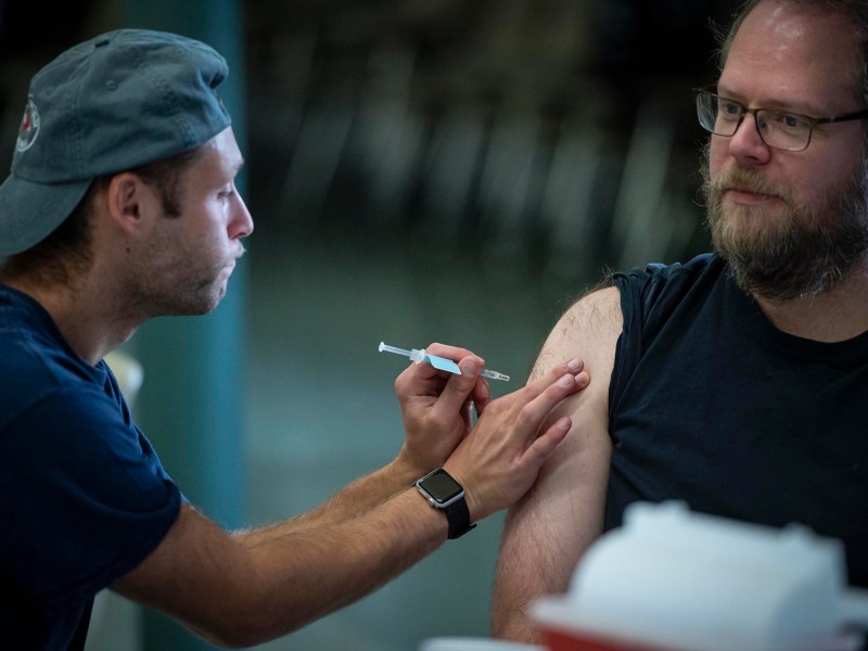 A man is getting a vaccine from another man.