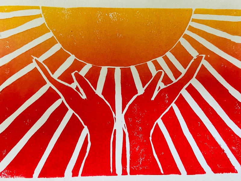 Two hands are raised upward, appearing to hold a large sun with rays shining outward in shades of yellow, orange, and red.